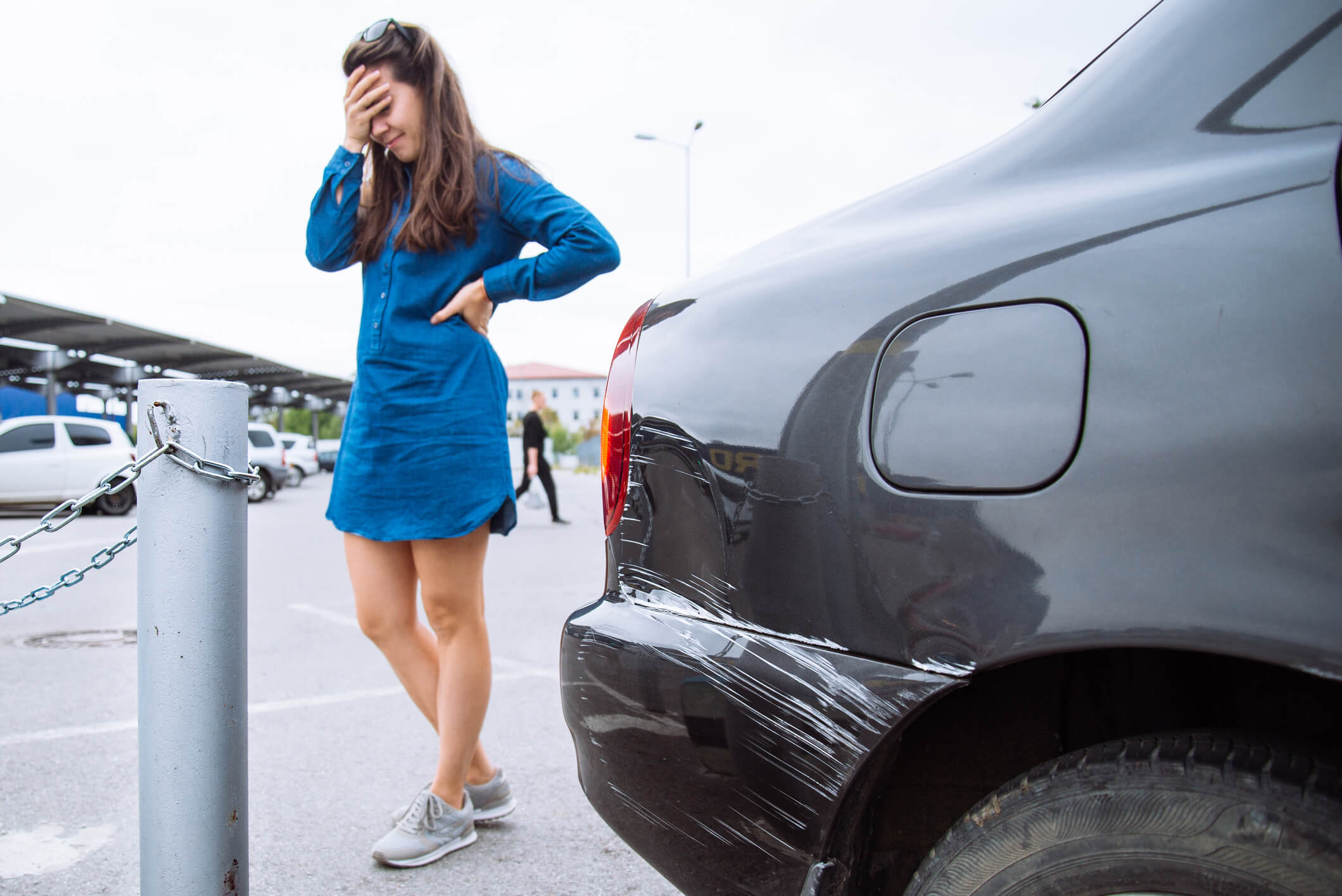 a woman in a blue dress is distressed in the background as her car has gotten into a vehicle accident